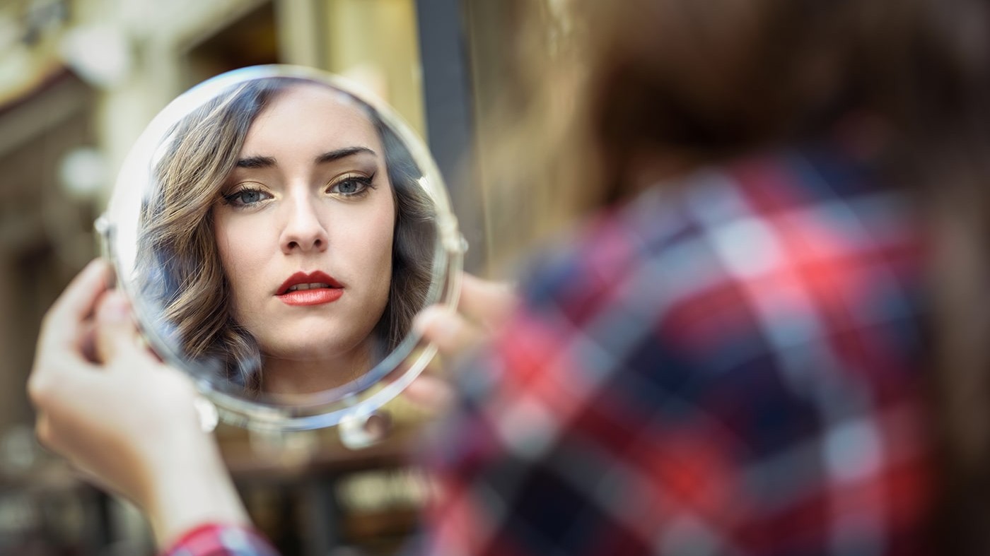 Woman looking at imitation of herself in mirror